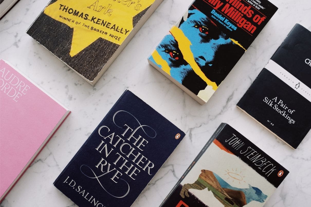 A stack of books on a marble surface, showcasing a diverse collection of literary works.